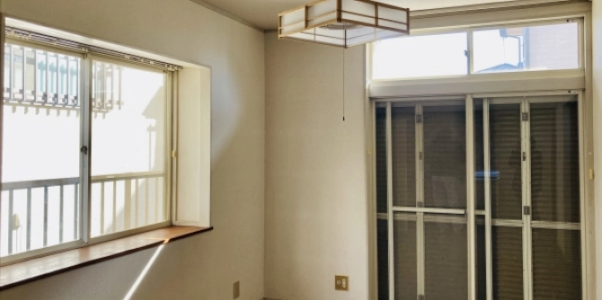 Bright empty room with a sliding glass door to a balcony, two large windows, and a ceiling light, sunlight streaming in.