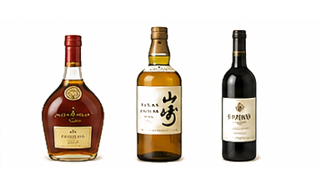 Three alcohol bottles lined up on a pale background: bourbon left, whiskey center, red wine right.